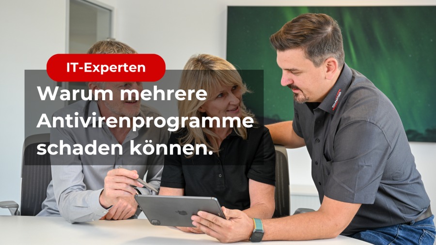 Zu sehen sind drei Mitarbeitende stehen beisammen und beraten sich an einem Microsoft Surface. Im Vordergrund ist ein Schriftzug "Warum mehrere Antivirenprogramme schaden können."