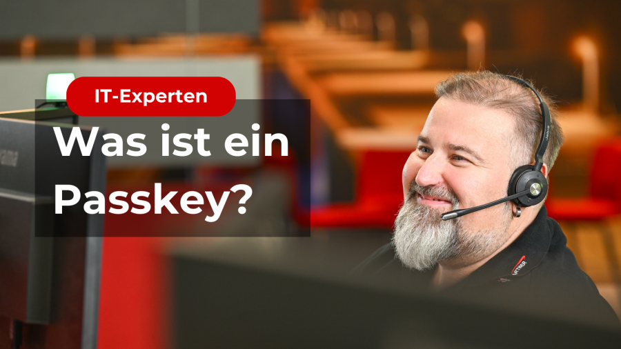 Zu sehen ist ein Schriftzug "Was ist ein Passkey?". Dahiter ist ein Mann der freundlich auf den Bildschirm schaut und ein Headset auf hat.