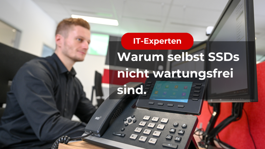 Zu sehen ist ein Text mit der Aufschrift: „IT-EXPERTEN Warum selbst SSDs nicht wartungsfrei sind.“ Im Hintergrund erkennt man ein Telefon mit Eingabemodul. Dahinter sitzt ein blonder Mann, der auf zwei Bildschirme blickt.