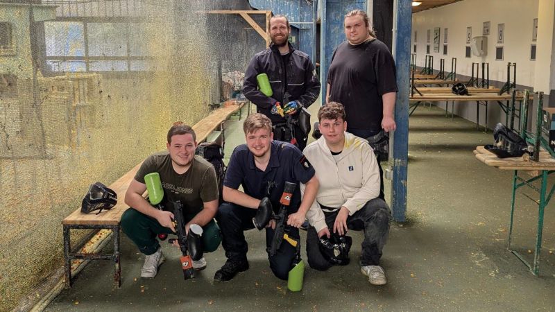 Gruppenfoto der Auszubildenden der EDV-PARTNER GmbH. Sie sind lässig gekleidet und halten Paintball-Markierer – aufgenommen in entspannter Freizeitstimmung.