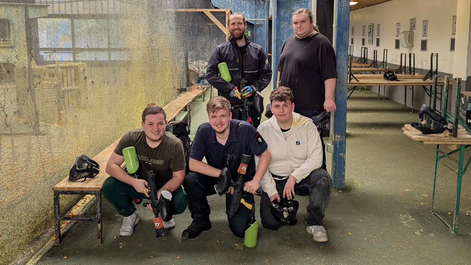 Gruppenfoto der Auszubildenden der EDV-PARTNER GmbH. Sie sind lässig gekleidet und halten Paintball-Markierer – aufgenommen in entspannter Freizeitstimmung.