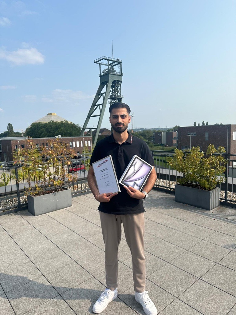 Mitarbeiter des Halbjahres Mohammed Saleha hält ein Tablet und seine Auszeichnung als Mitarbeiter des Halbjahres.