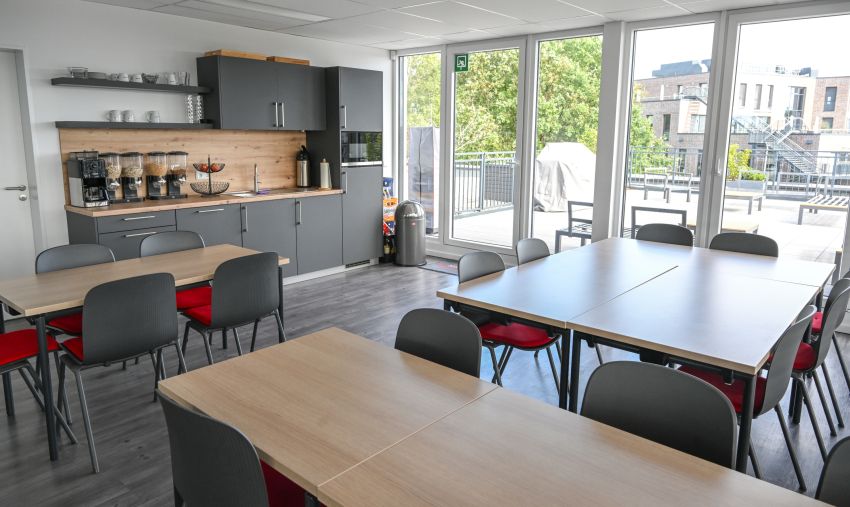 Foto des Pausenraums mit Zugang zur Dachterrasse und einer offenen Küche.
