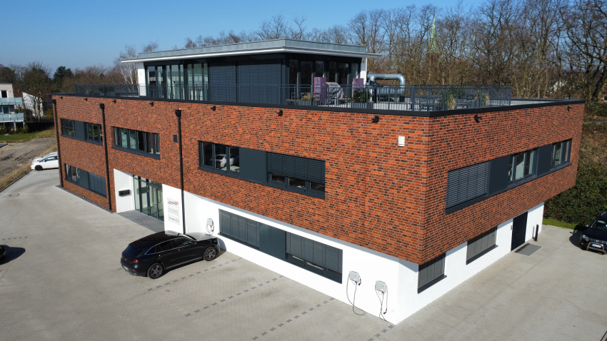 Modernes, dreigeschossiges Bürogebäude mit roter Klinkerfassade und Flachdach, aufgenommen aus der Vogelperspektive.